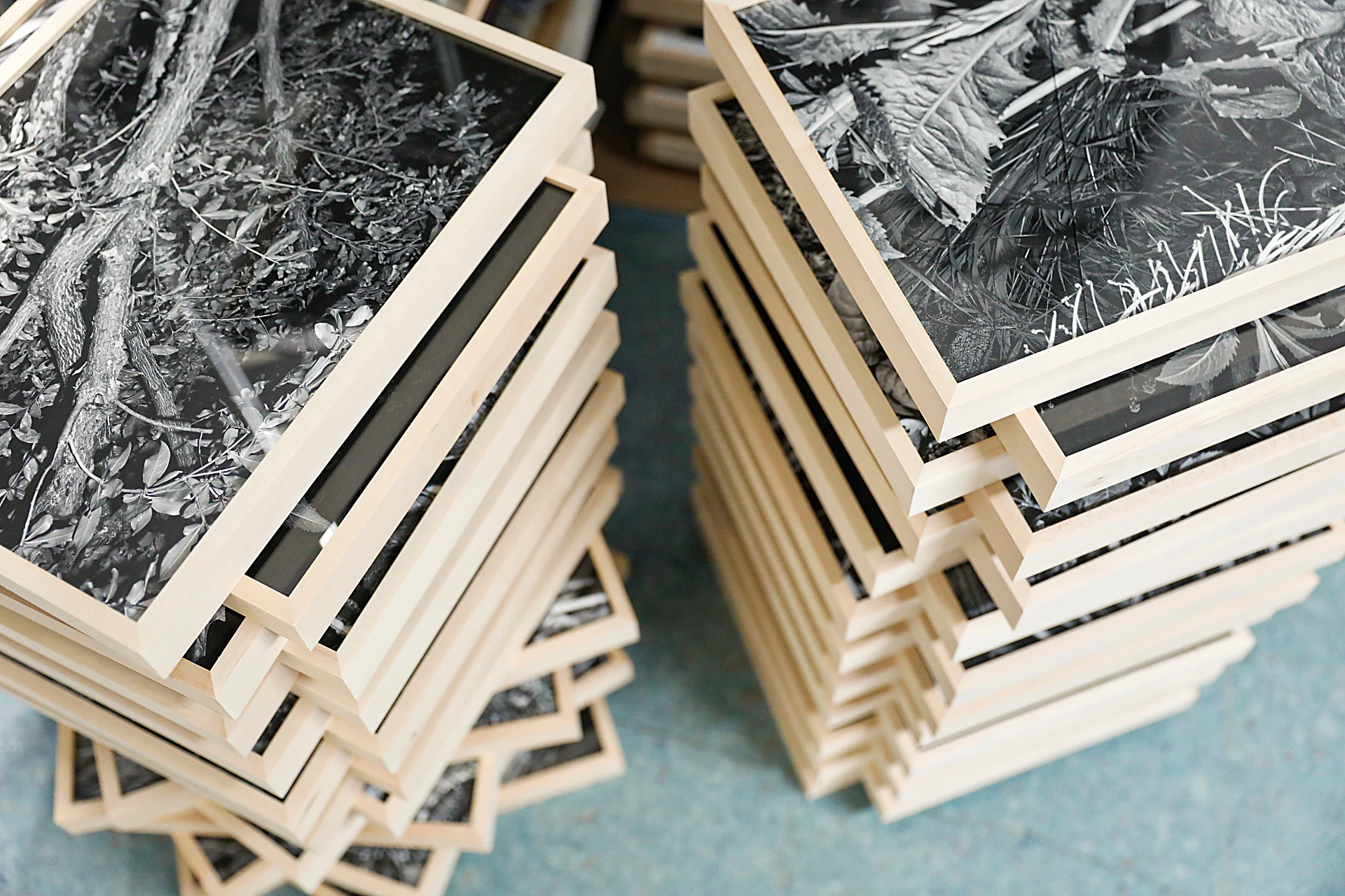 Pile di cornici artigianali in fase di finitura e controllo qualità per l'allestimento della mostra del fotografo Benassi